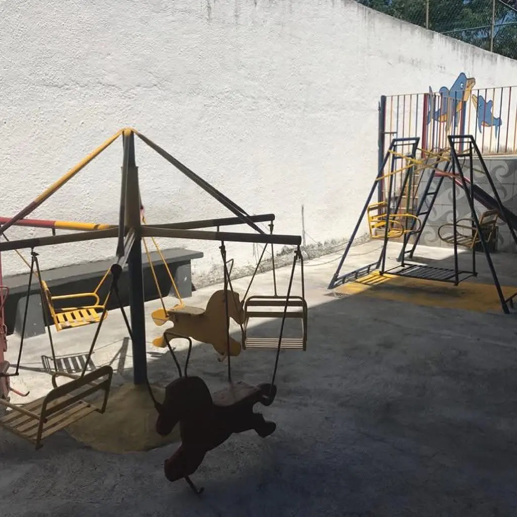 Pátio externo com balanços, escorrega e área de recreação